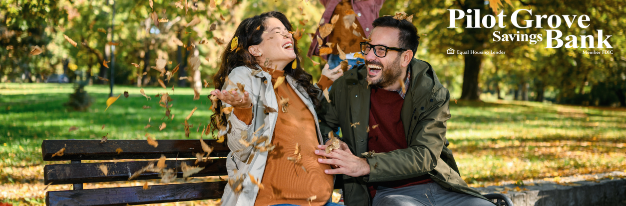 Couple in the park throwing leaves in the air, enjoying the fall weather.