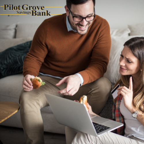 A couple who is looking at checking account options from Pilot Grove Savings Bank on their computer.